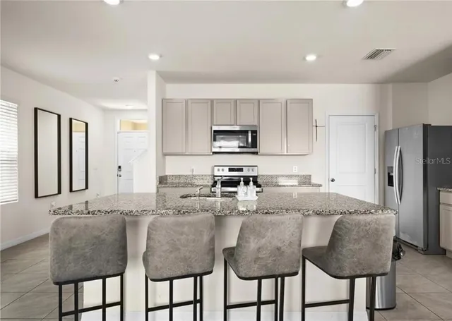 a kitchen with granite countertop a center island a sink stainless steel appliances and cabinets