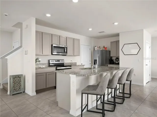 a kitchen with microwave a refrigerator and furniture