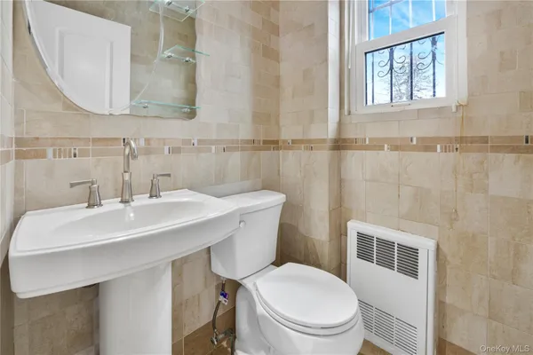a bathroom with a sink a mirror a toilet and a window