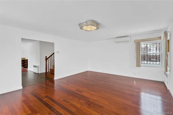 a view of empty room with window and wooden floor