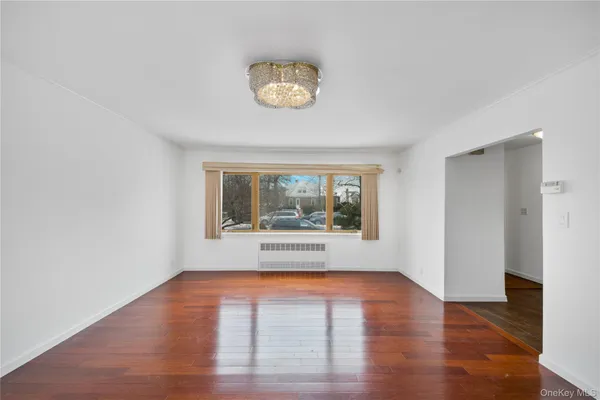 a view of an empty room with a window and wooden floor
