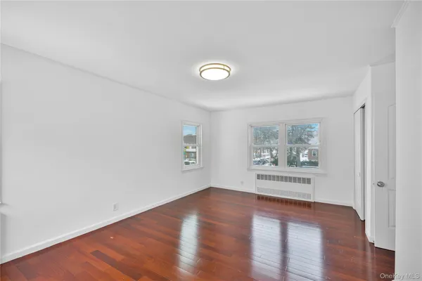 a view of empty room with window and wooden floor