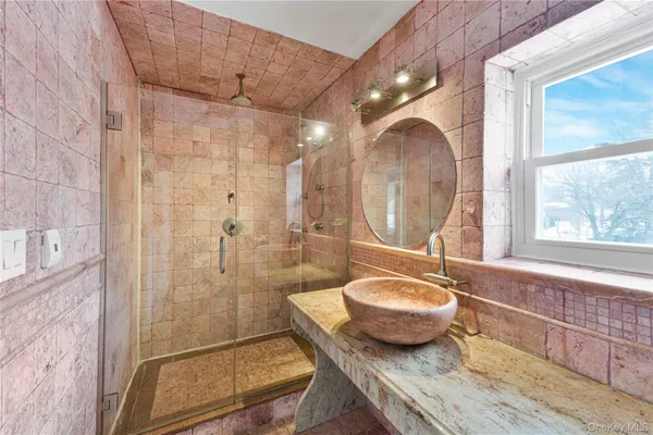 a bathroom with a granite countertop sink a mirror and a shower
