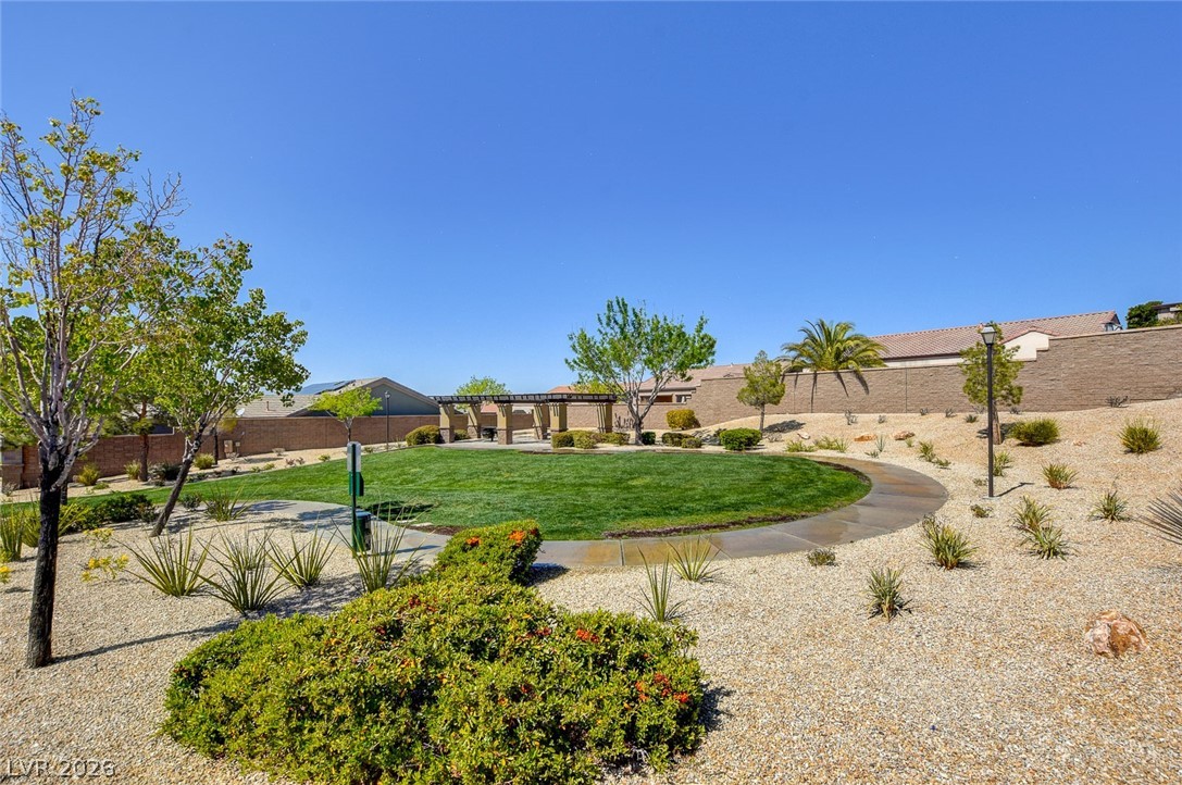 2793 Rosenhearty Drive Henderson, NV 89044 - Photo 74 of 85 A well-maintained community park features a manicured lawn, meandering pathway, and diverse plantings under an open sky.