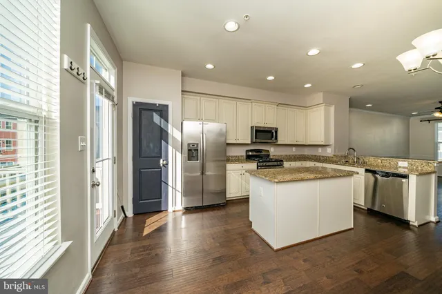 a kitchen with stainless steel appliances granite countertop a refrigerator a sink a stove and oven