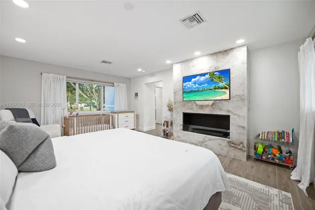 a bedroom with a bed a ceiling fan and a flat screen tv