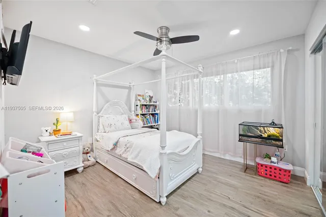 a bedroom with a bed a flat screen tv and a chandelier