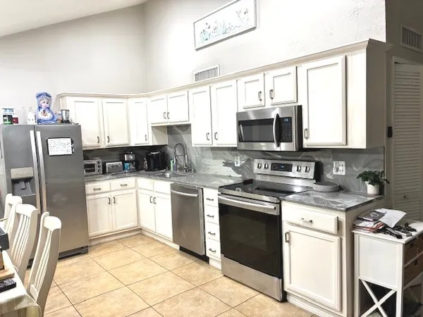 a kitchen with stainless steel appliances granite countertop a stove top oven a sink dishwasher and a refrigerator