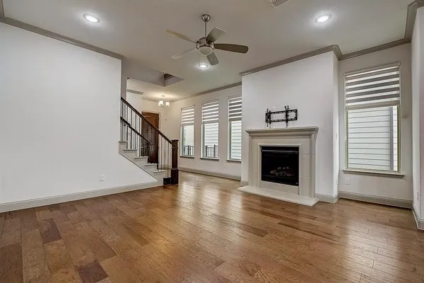 an empty room with wooden floor a fireplace and windows