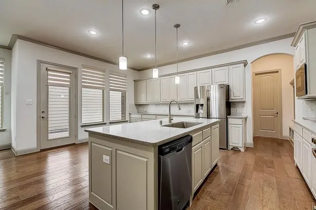 a kitchen with a sink a counter top space stainless steel appliances and wooden floor