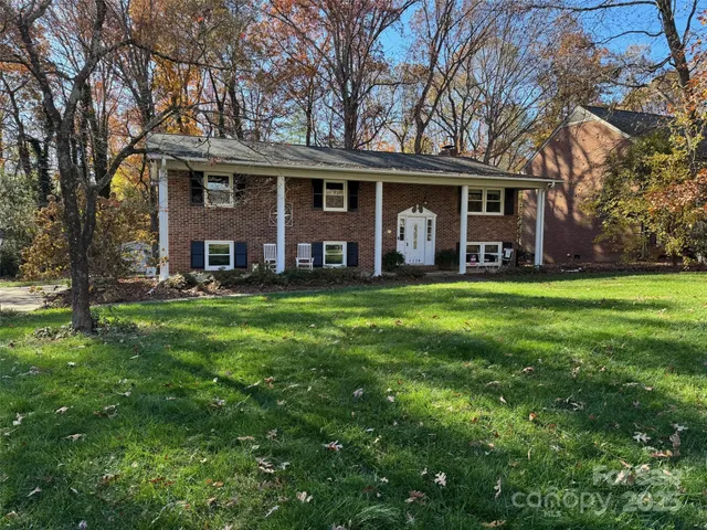 front view of a brick house with a big yard and large trees