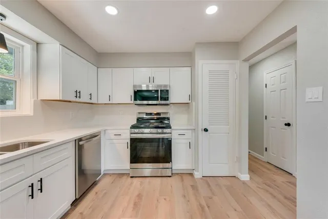 a kitchen with a sink cabinets stainless steel appliances and a window