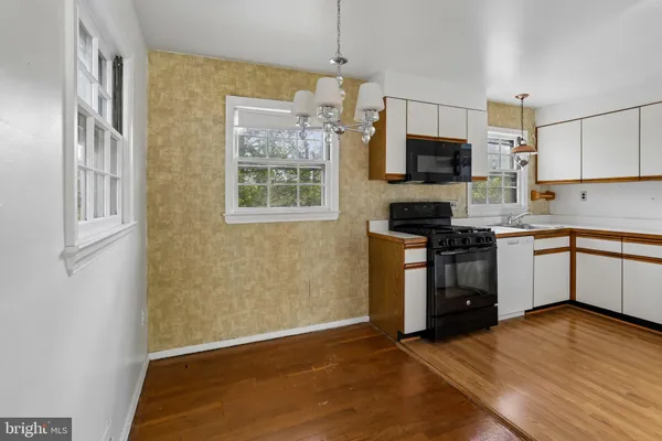 a kitchen with stainless steel appliances a stove top oven a sink a refrigerator white cabinets and wooden floor