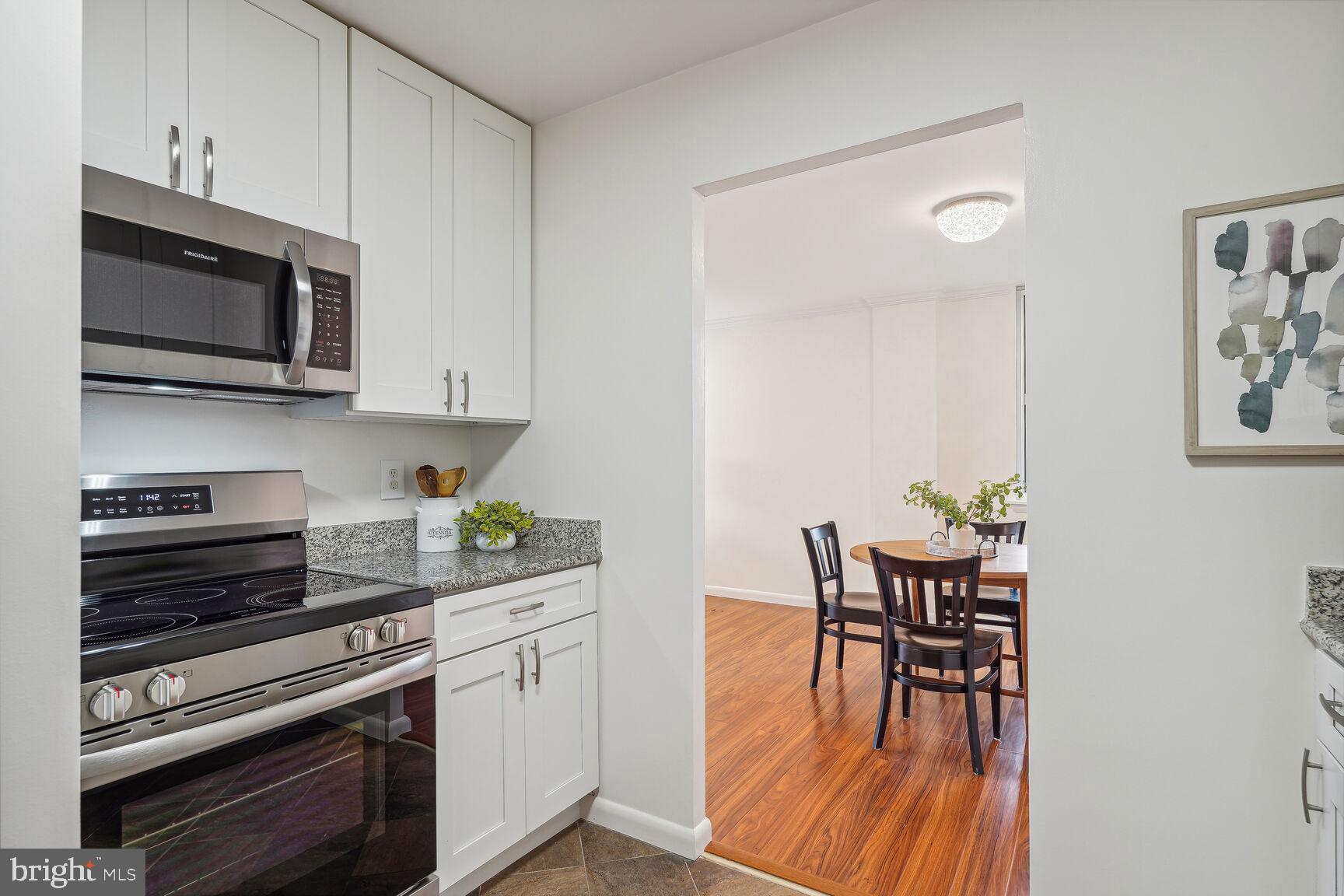 3245 Rio Drive, Unit 915 Falls Church, VA 22041 - Photo 8 of 31 a kitchen with stainless steel appliances a white table chairs and a microwave