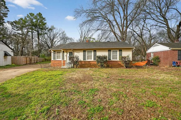 a front view of a house with a yard and trees