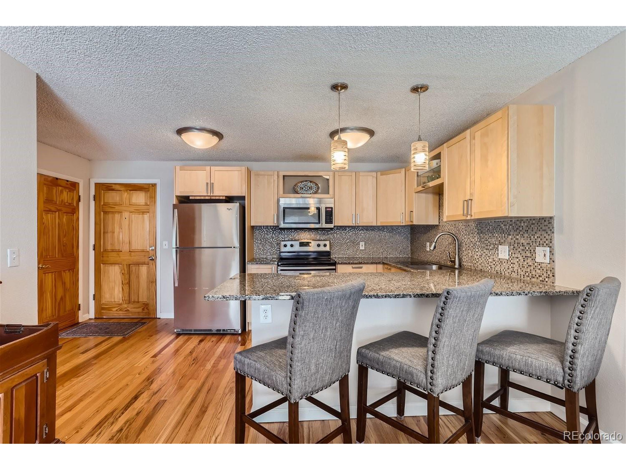 a kitchen with stainless steel appliances granite countertop a table chairs refrigerator and a sink