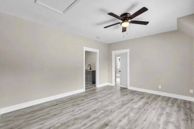 an empty room with wooden floor and ceiling fan