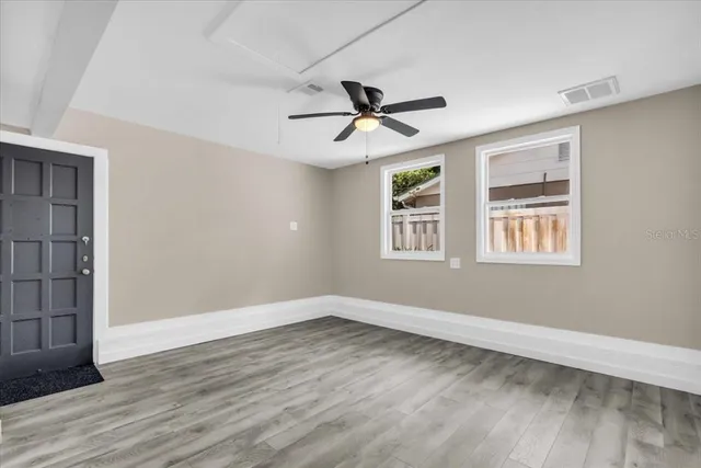 a view of empty room with wooden floor and fan