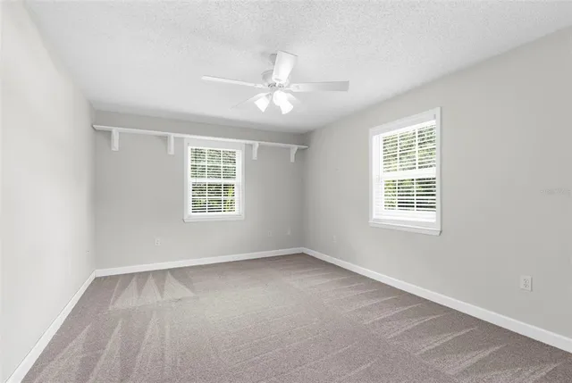 a view of an empty room with wooden floor and a ceiling fan