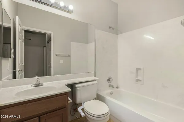 a bathroom with a bathtub shower sink vanity mirror and toilet