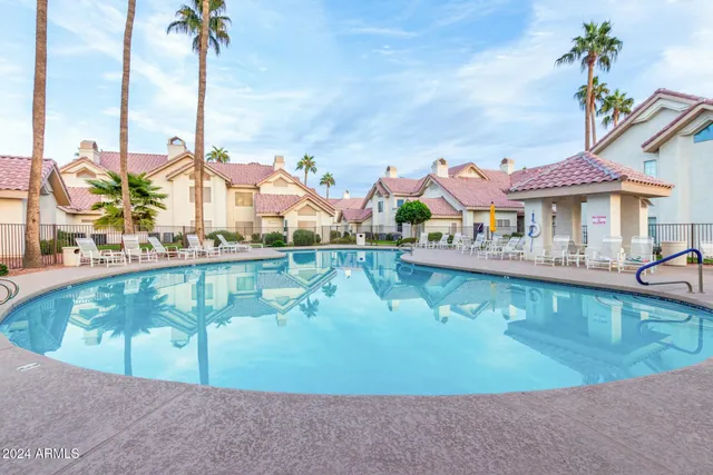 a view of a swimming pool with a lawn chairs under an umbrella