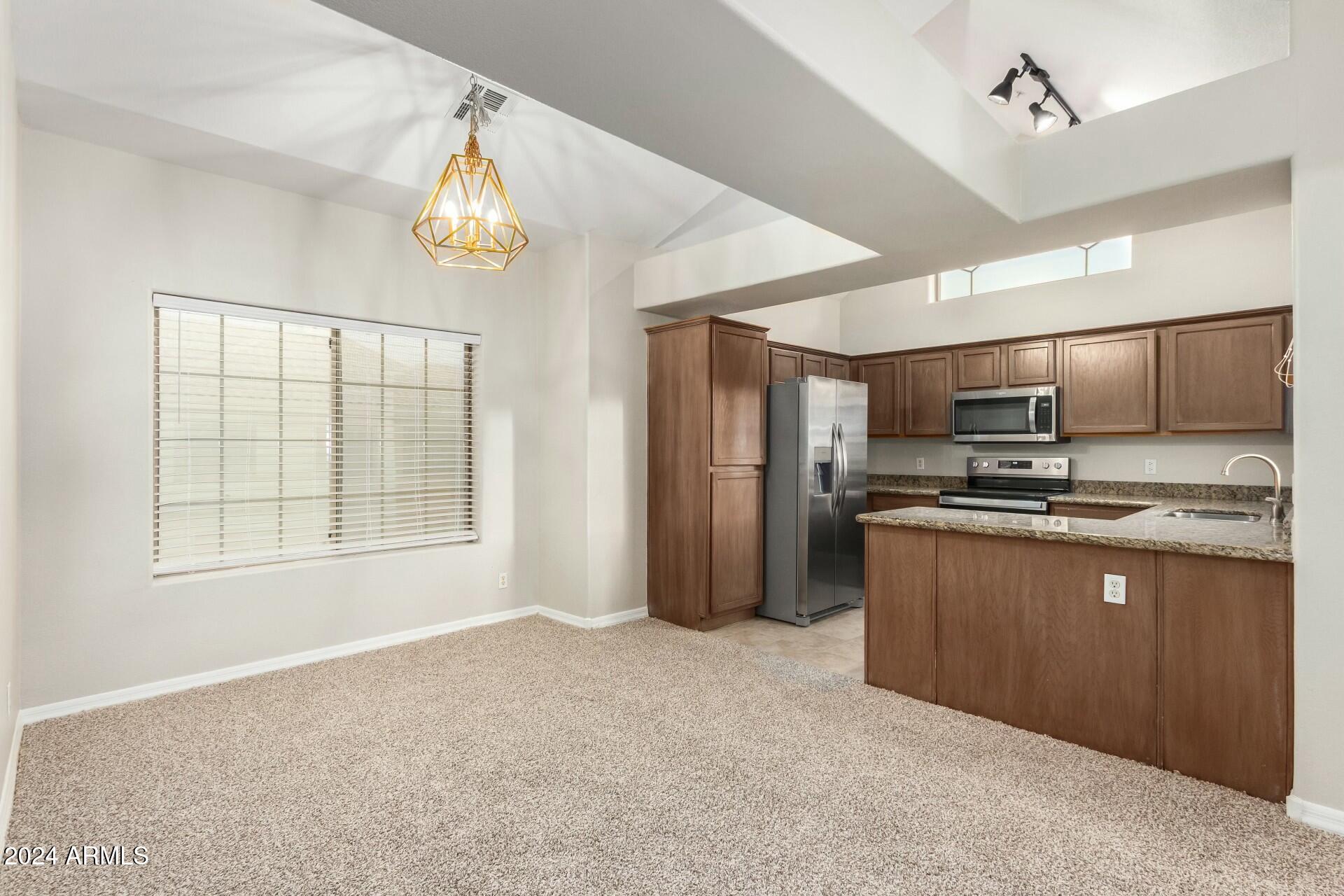 2801 North Litchfield Road, Unit 18 Goodyear, AZ 85395 - Photo 5 of 21 a kitchen with stainless steel appliances granite countertop a refrigerator and a stove top oven