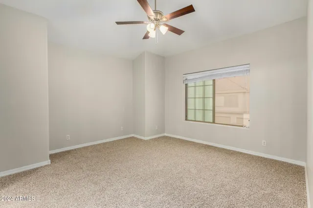 an empty room with a window and a fan