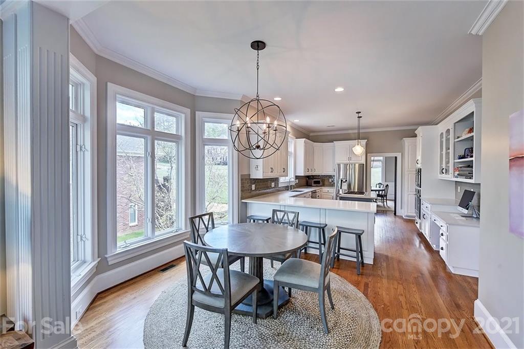 18731 River Falls Drive Davidson, NC 28036 - Photo 13 of 45 a dining room with wooden floor a chandelier a wooden table and chairs