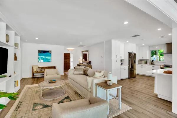 a living room with furniture kitchen view and a flat screen tv