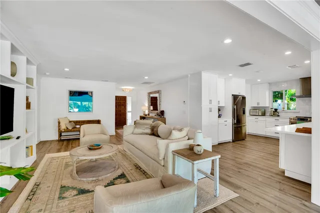 a living room with furniture kitchen view and a flat screen tv