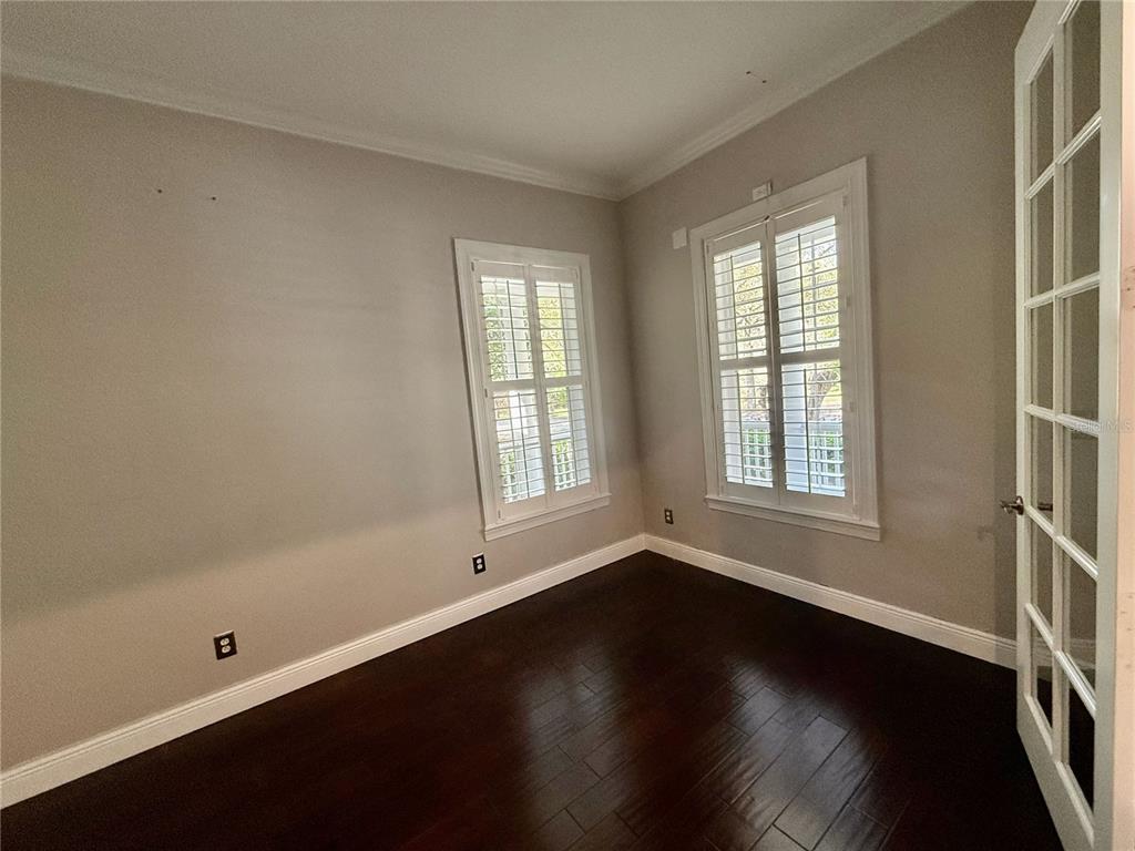 1328 Celebration Avenue Celebration, FL 34747 - Photo 14 of 26 an empty room with wooden floor and windows with curtains