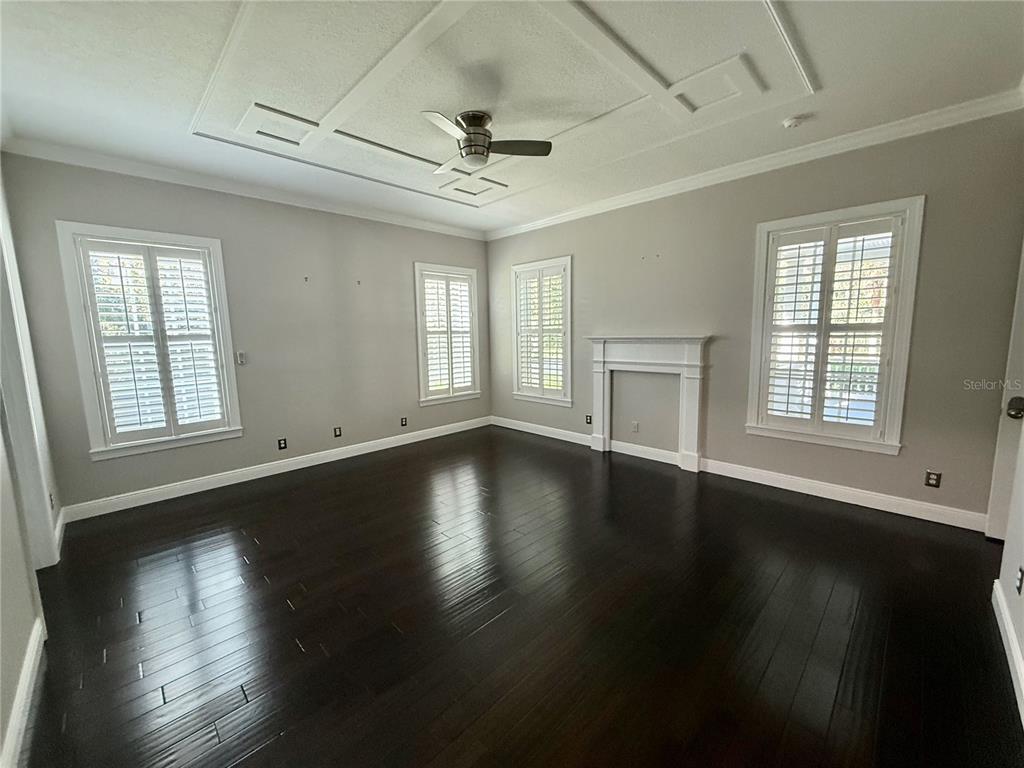 1328 Celebration Avenue Celebration, FL 34747 - Photo 16 of 26 an empty room with wooden floor chandelier fan and windows
