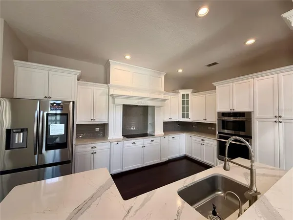a kitchen with stainless steel appliances a sink a stove a refrigerator and cabinets