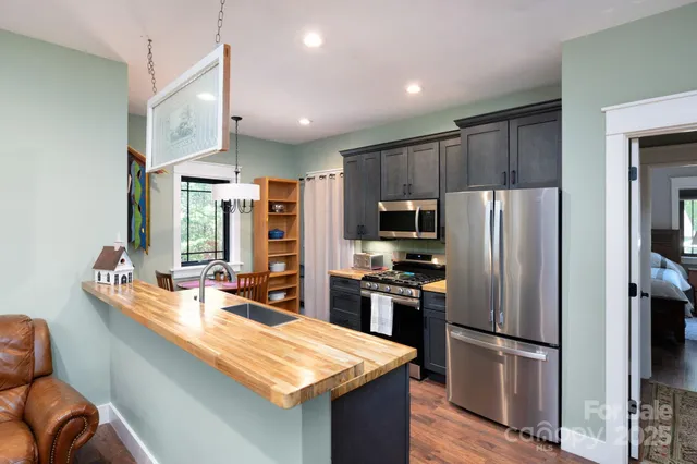 a kitchen with stainless steel appliances granite countertop a refrigerator a stove top oven a sink dishwasher and wooden cabinets with wooden floor