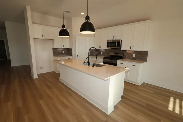 a kitchen with stainless steel appliances a sink a stove a microwave and wooden floor