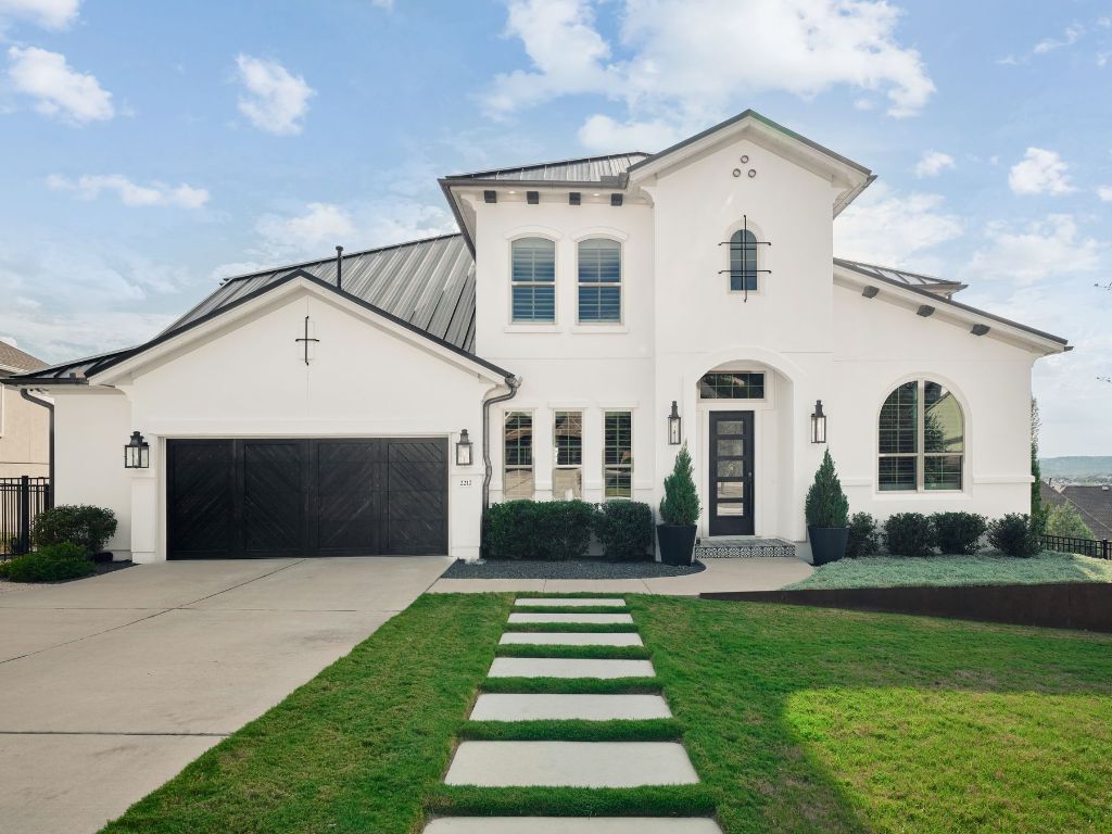 a front view of a house with a yard and potted plants
