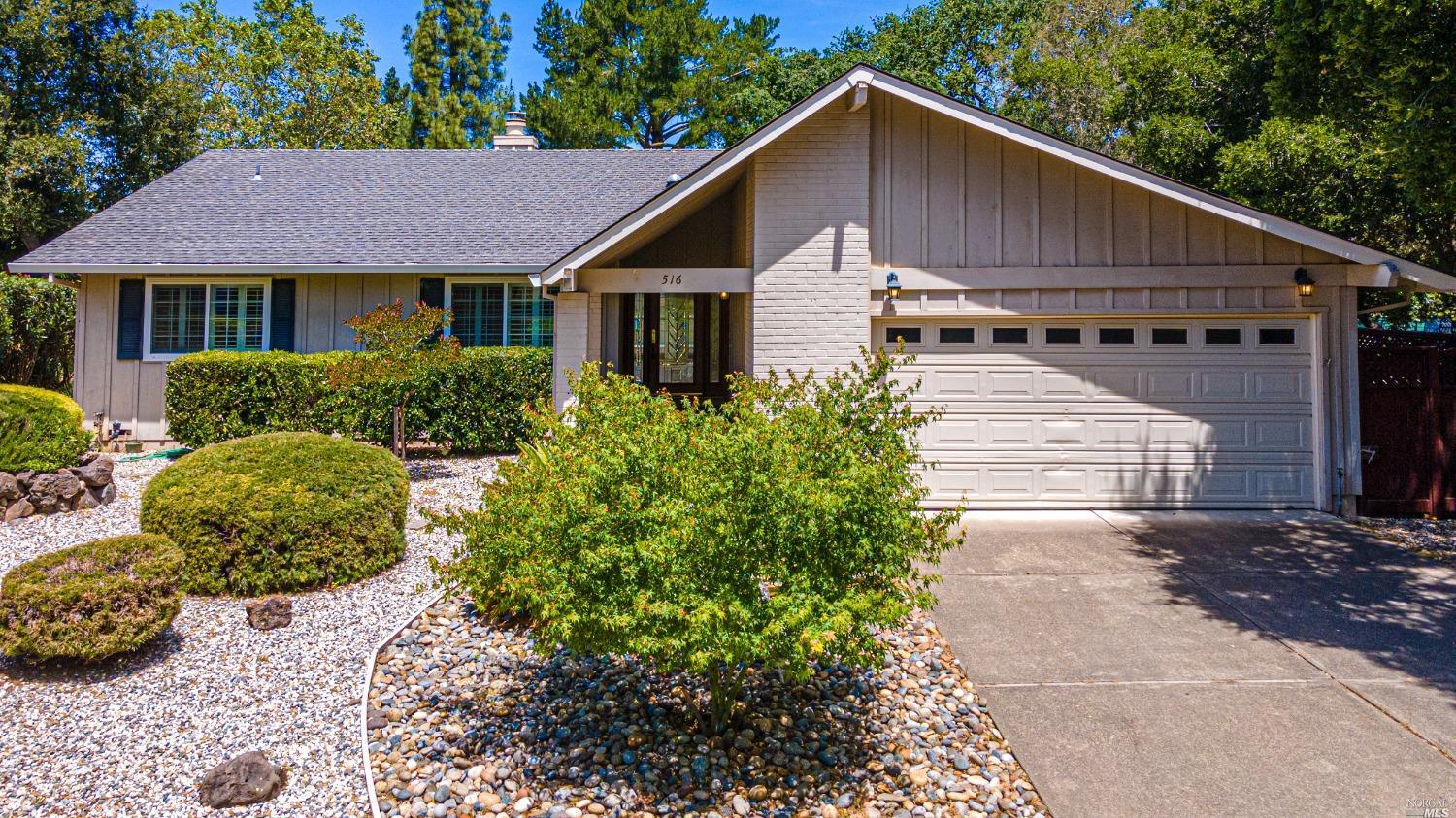 a view of a house with a yard plants and large tree