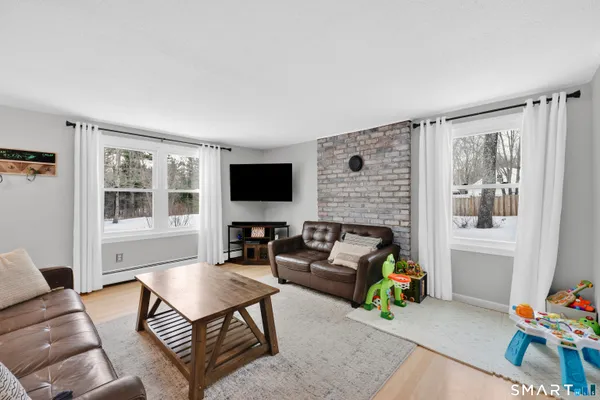 a living room with furniture a flat screen tv and a window