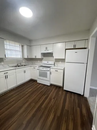 a kitchen with wooden floors and white appliances
