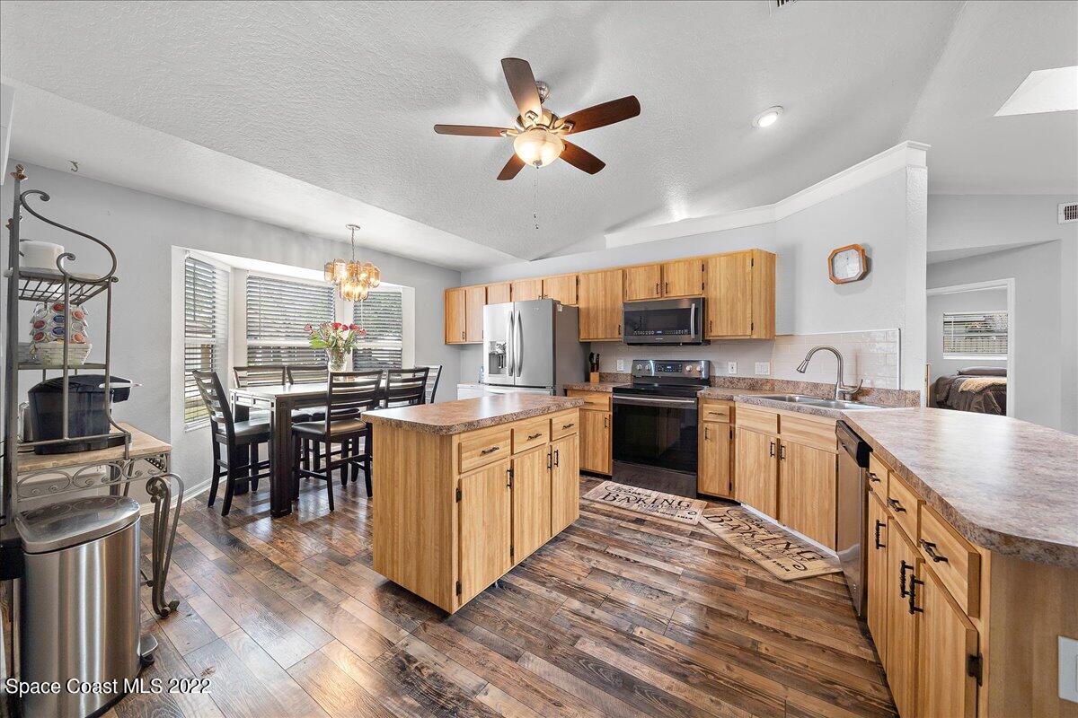 6165 Corning Road Cocoa, FL 32927 - Photo 10 of 44 a kitchen with granite countertop a stove top oven a sink dishwasher a dining table and chairs with wooden floor