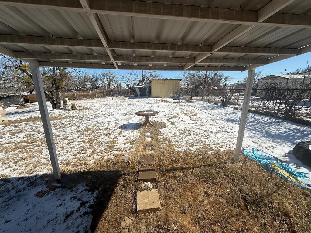 304 Neblett Street Eastland, TX 76448 - Photo 14 of 15 Snowy yard with a storage shed and a fenced backyard