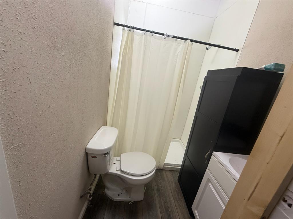 304 Neblett Street Eastland, TX 76448 - Photo 7 of 15 Bathroom featuring a textured wall, a shower with shower curtain, dark wood-style floors, and vanity