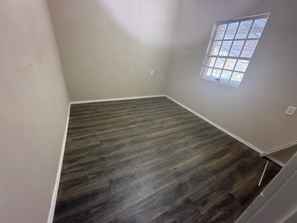 304 Neblett Street Eastland, TX 76448 - Photo 8 of 15 Unfurnished room with dark wood-style flooring and baseboards