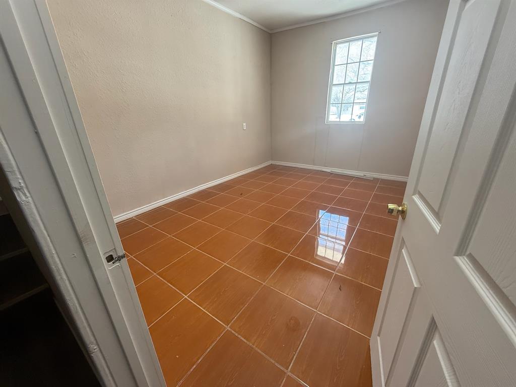 304 Neblett Street Eastland, TX 76448 - Photo 9 of 15 Unfurnished room with tile patterned floors and ornamental molding