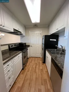 a view of a big room with wooden floor and a kitchen