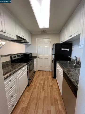 a view of a big room with wooden floor and a kitchen