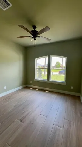 a view of an empty room with a window and wooden floor