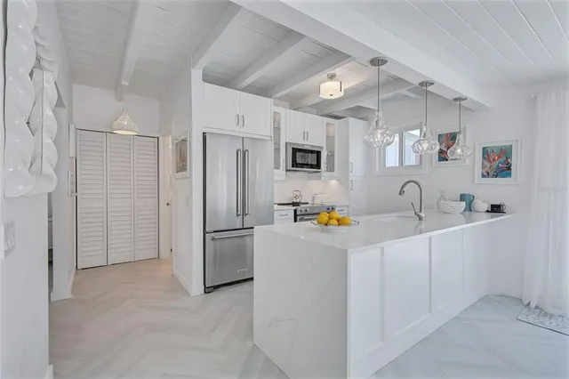 a kitchen with stainless steel appliances a refrigerator a sink a stove top oven a counter space and cabinets