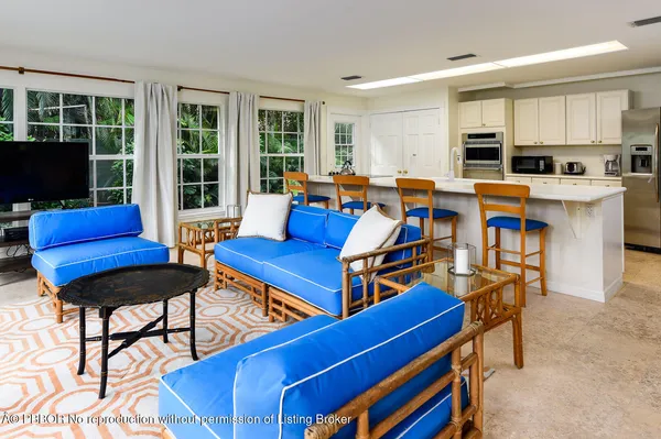 a living room with furniture kitchen view and a large window