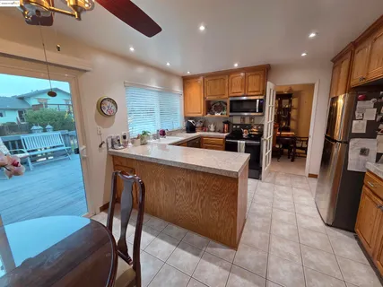 a kitchen with stainless steel appliances granite countertop a table chairs and a refrigerator
